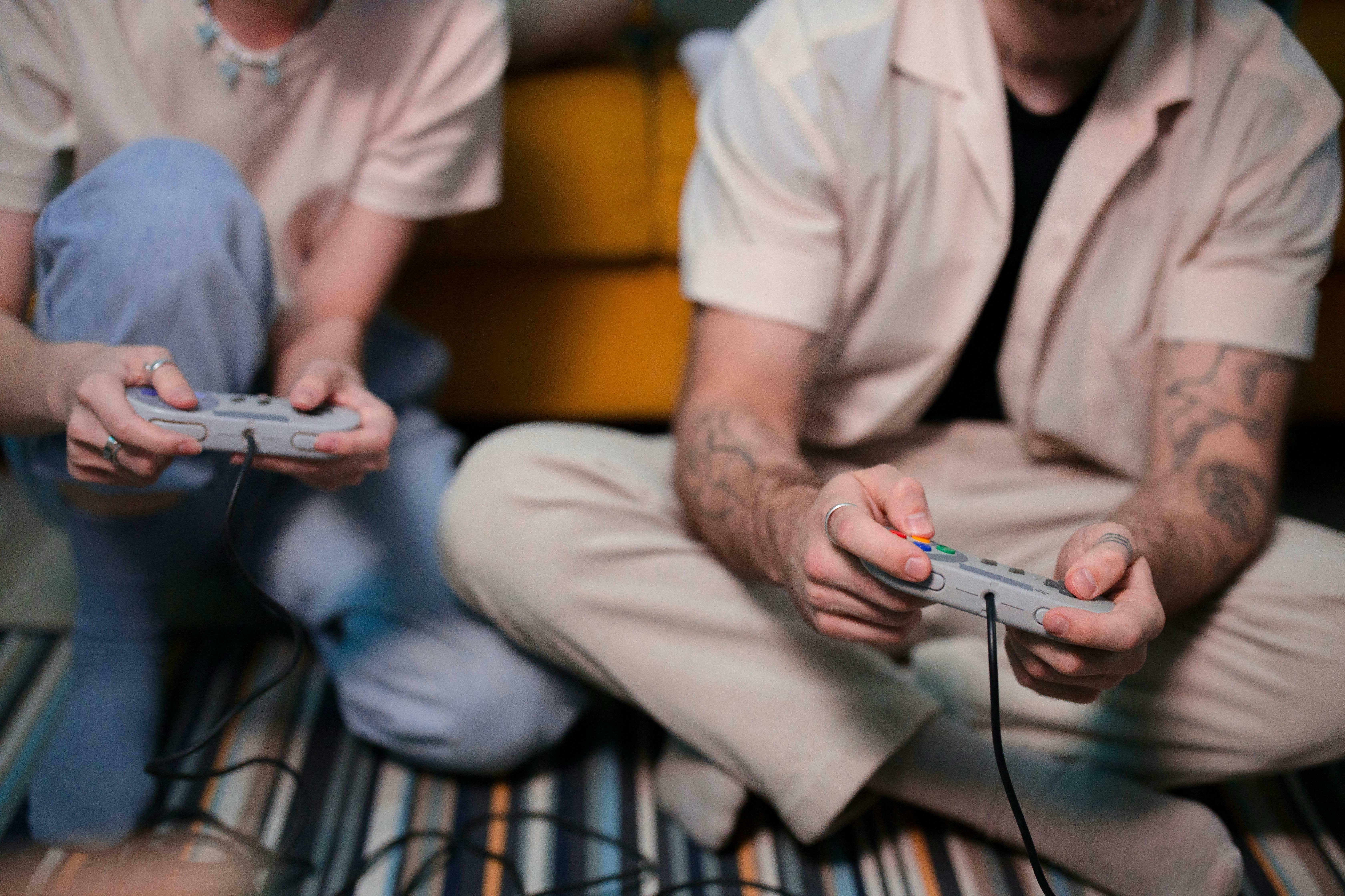 deux personnes tiennent une manette de console de jeu vidéo dans leur main