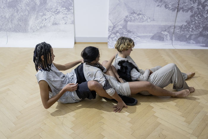 trois personnes sont assises les unes derrière les autres dans une salle d'exposition