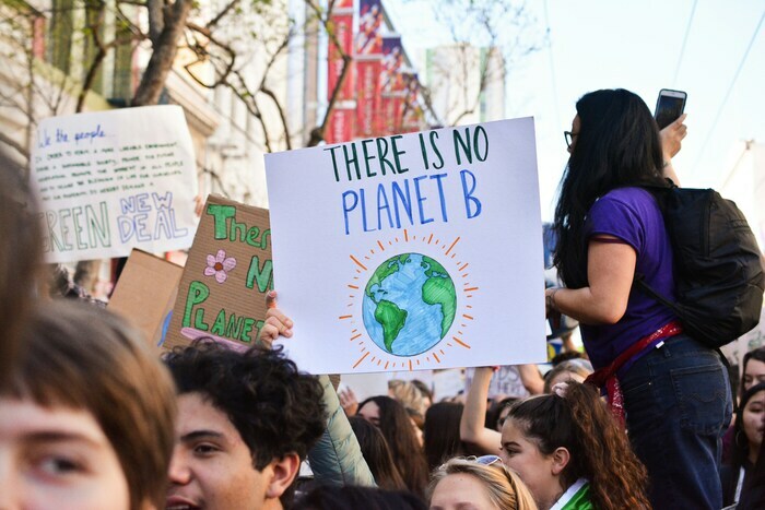 Une manifestation avec des personnes ' age et d' origine differentes et une pancarte "Il n' y a pas de planet B" ecrite en anglais