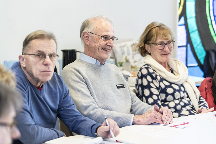 Des séniors sont assis autour d'une table et sourient