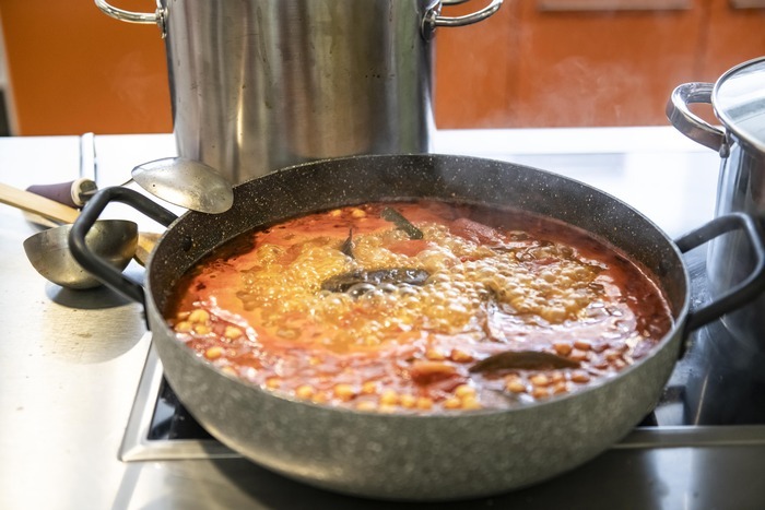 Un plat est en train de cuire sur une cuisinière, avec des casseroles autour