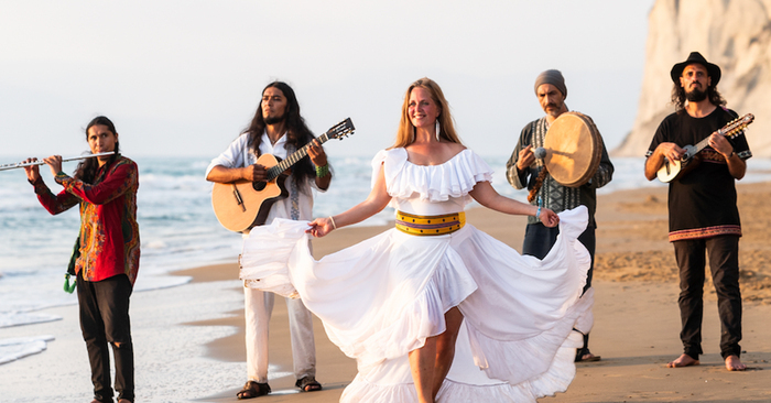 Les membres du groupe marche sur une plage en jouant de leurs instruments