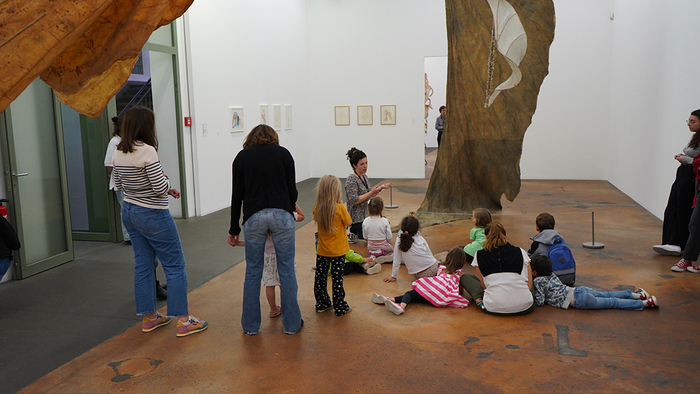 Enfants et parents en visite au MAMCO. Les participants sont installés devant les oeuvres de l'artiste Erica Pedretti.