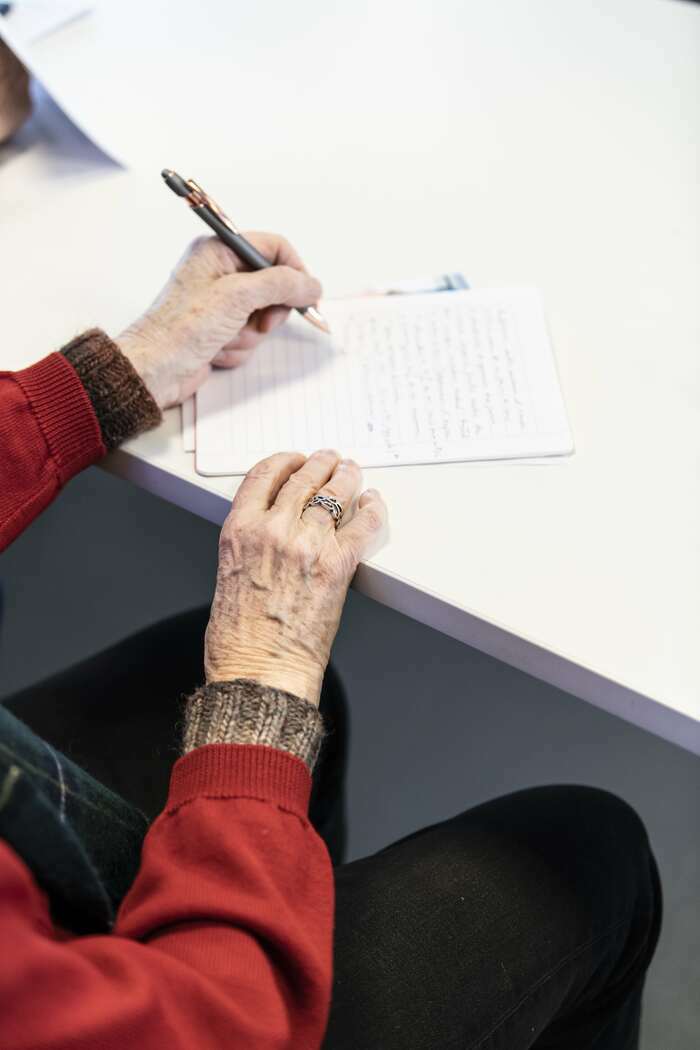 une personnes assise devant une table est en train de prendre des notes