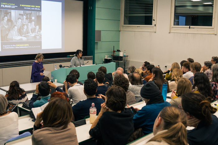 Aula universitaire remplie d'étudiantes et d'étudiants regardant vers le tableau.