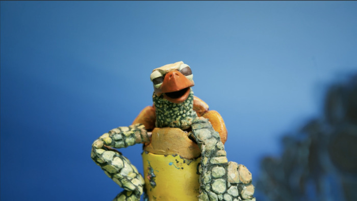 Une tortue qui se tient debout se tient la hanche avec le bras, sur un fond bleu.