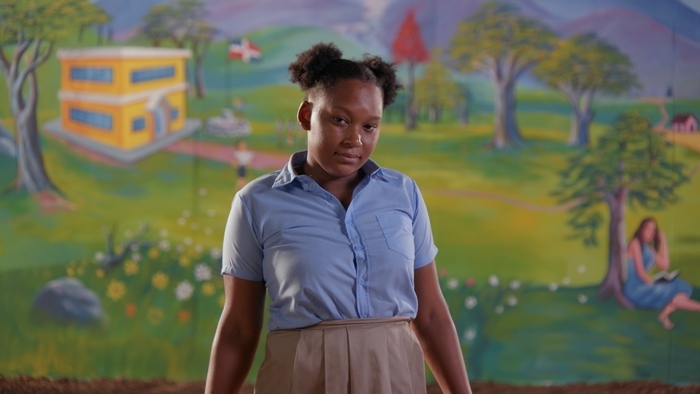 A young girl against a backdrop of colorful frescoes.