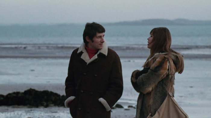 Un couple au bord de la mer en hiver converse tranquillement.