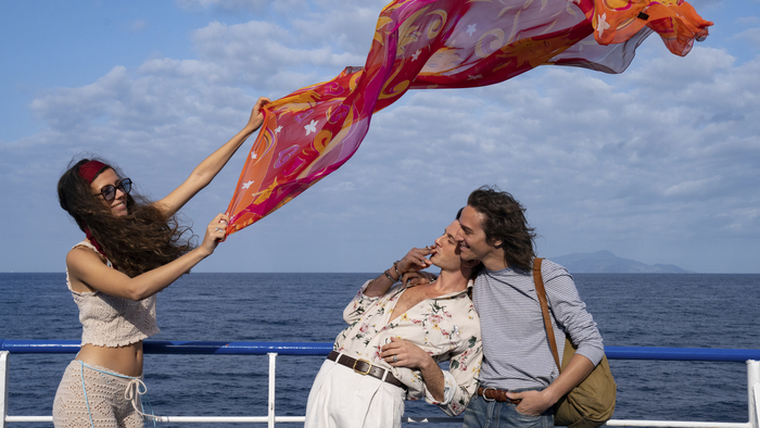 Trois jeunes gens jouent avec un foulard sur un bateau en Méditerranée.