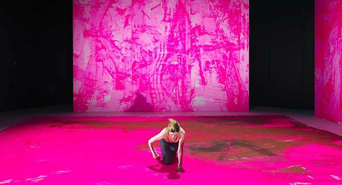 une femme seul au centre de l'image avance à quatre pattes dans un décor tout fait de rose.