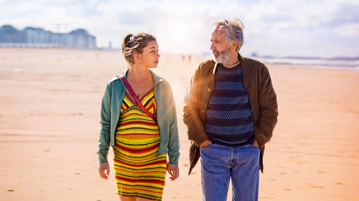 Une femme enceinte et un homme se marchant sur une plage.