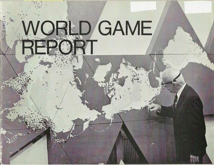 Sur cette image en noir et blanc on voit un homme en costume qui touche du doigt une carte du monde qui a été dessinée sur des triangles placés au mur. L'homme semble âgé. La carte du monde est difficilement reconnaissable. Les mots WORLD GAME REPORT sont inscrits en grand sur la partie supérieure gauche de l'image.