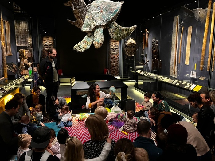 Un groupes d'enfant et d'adultes devant une animatrice dans l'exposition permanente du MEG à Genève.