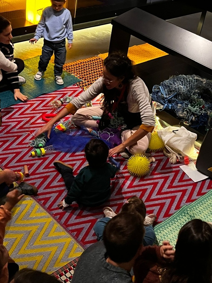 Un groupes d'enfant et d'adultes devant une animatrice dans l'exposition permanente du MEG à Genève.