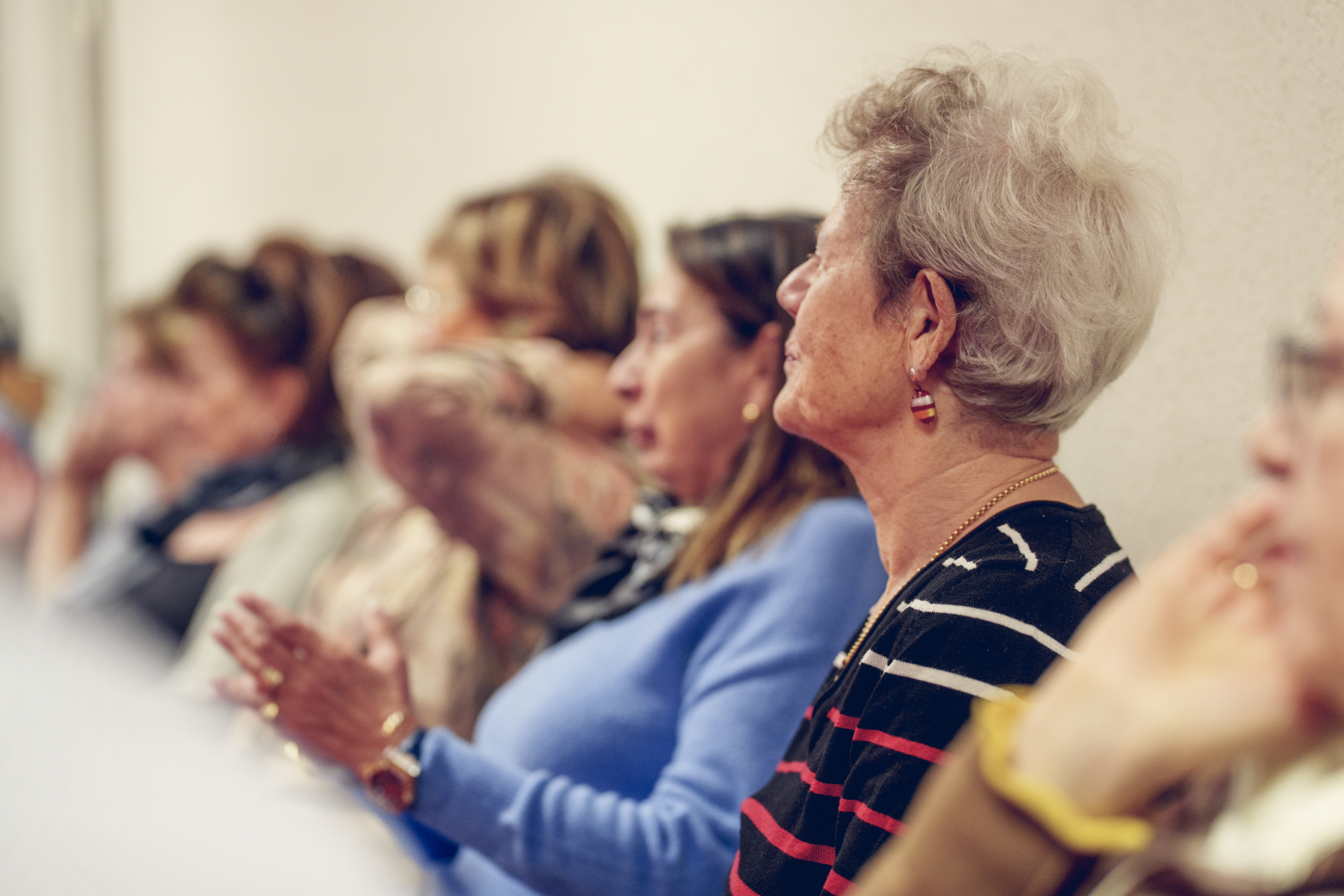 4-5 personnes âgées alignées de profil qui regardent un conférencier.