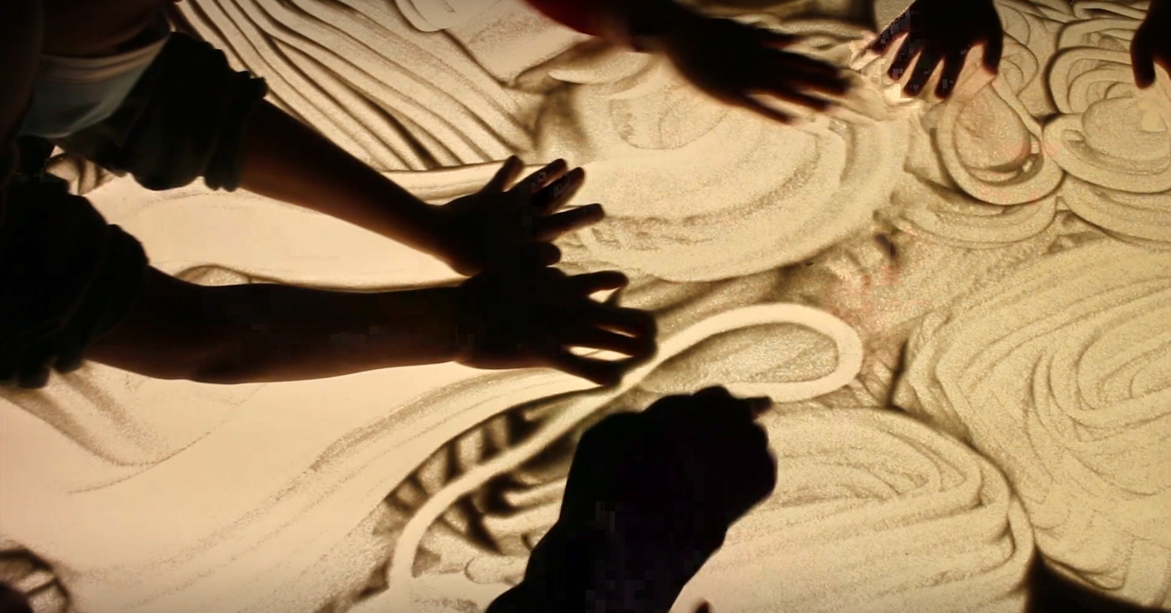 Photo de mains qui manipulent le sable sur une table lumineuse