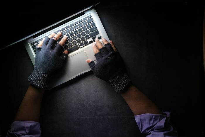 Des mains avec des mitaines utilisent le clavier d'un ordinateur portable