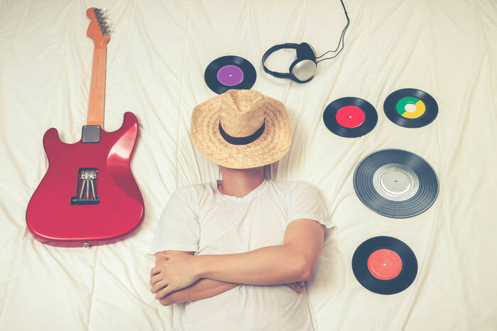 Une personne dort entouré de vinyles et d'une guitare électrique