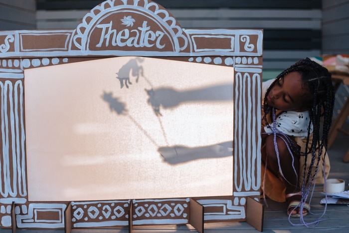 petite fille qui joue avec un théâtre d'ombres