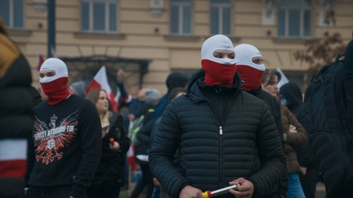 Manifestants masqués en blanc et rouge, couleurs du drapeau polonais, lors d'un rassemblement.