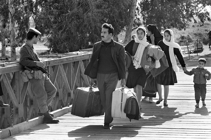 Des réfugiés palestiniens traversent le pont Allenby, fuyant la Cisjordanie vers la Jordanie lors de la guerre des Six Jours en 1967. Cette image illustre l'exode massif de milliers de familles, forcées de quitter leurs foyers sous la menace du conflit, symbolisant la tragédie humaine de la guerre et la quête incessante de sécurité.