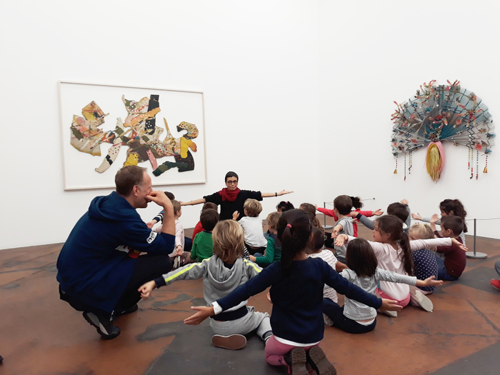 Enfants en visite dans une des salles d'exposition du MAMCO. Ils sont en train d'imiter l'ouverture d'un éventail.