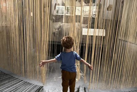 Un enfant joue avec des rideaux dans une exposition du MEG.