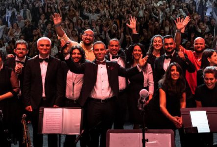 Photo de l'orchestre dos au public avec les mains en l'air