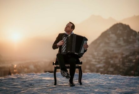 Yves Moulin et son accordéon au lever du soleil dans les montagnes enneigées