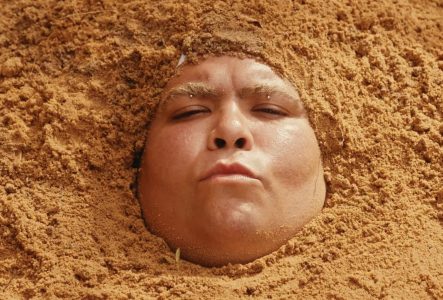 Portrait de l'artiste dont la tête est immergée dans du sable