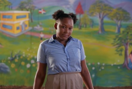 Une jeune fille sur un fond de fresque colorée.