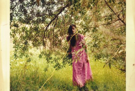 DR Une photo usée d'une jeune femme habillé en rose sous un arbre