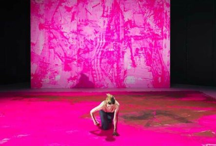 une femme seul au centre de l'image avance à quatre pattes dans un décor tout fait de rose.