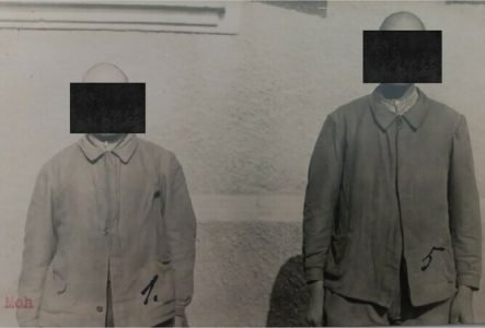 Deux hommes en uniformes de prisonniers sont face caméra. Leurs visages sont masqués par un carré noir afin de protéger leur identité.