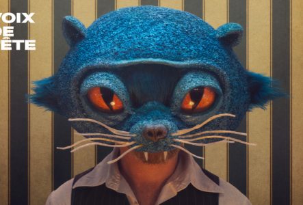 Photo de l'artiste avec un masque de chat bleu et de grands yeux oranges