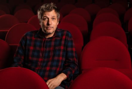 Nathanaël Rochat assis sur des chaises de théâtre rouge