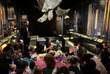 Un groupes d'enfant et d'adultes devant une animatrice dans l'exposition permanente du MEG à Genève.