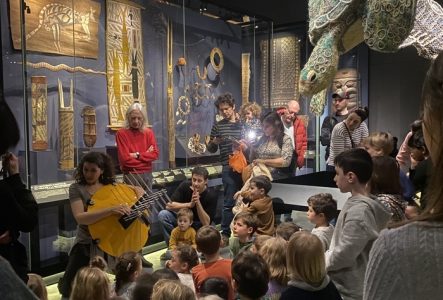 Un groupes d'enfant et d'adultes devant une animatrice dans l'exposition permanente du MEG à Genève.