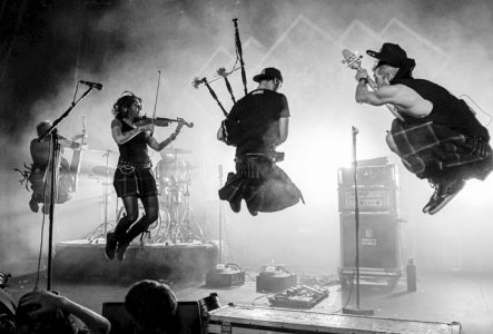 Photo du groupe Celkilt sur scène. Les musicien·ne·s sautent dans les airs avec leurs instruments dont une cornemuse, un violon, une guitare et une base.