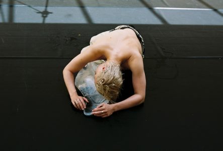 La danseuse Ola Maciejewska est couchée sur le sol. Elle est torse nu et tient dans ses bras une forme en glaçon.