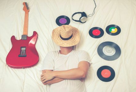 Une personne dort entouré de vinyles et d'une guitare électrique