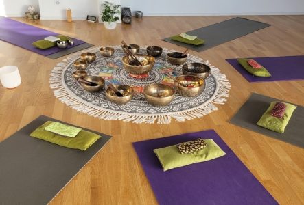 Tapis de yoga posé en cercle au sol avec des bols tibétains au milieu du cercle